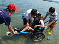 水陸両用の車いすを使って海に入る中学生