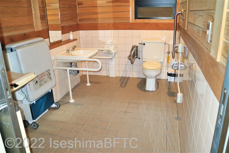 横山ビジターセンター車いす対応トイレ内部　入口からみて正面に、たて置きに便器。入口からみて左奥に洗面台